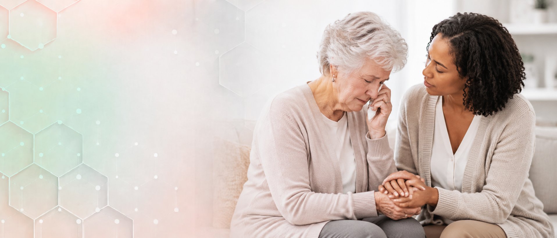 A woman offering comfort and holding the hands of an older woman